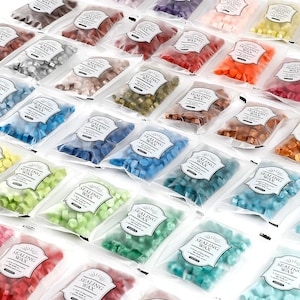 Op de afbeelding: Een assortiment kleurrijke laksparel in doorzichtige plastic zakjes. De zakjes zijn voorzien van het opschrift "SEALING WAX". Kleuren zijn onder meer rood, blauw, groen, oranje en bruin. De kralen zijn klein en zeshoekig.