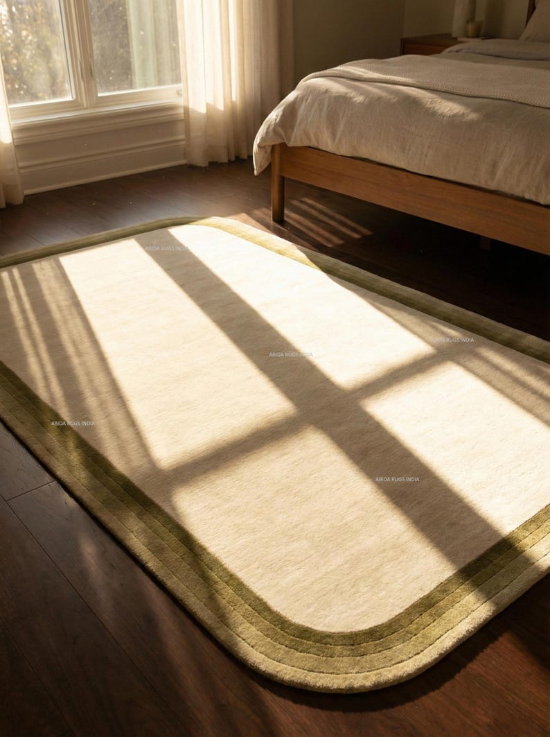 K&ouml;nnte beinhalten: Beiger rechteckiger Teppich mit abgerundeten Ecken und gr&uuml;nem Rand. Der Teppich liegt auf einem dunklen Holzboden in einem Schlafzimmer, mit Sonnenlicht, das durch ein Fenster scheint. Ungef&auml;hre Gr&ouml;&szlig;e: 200 cm x 300 cm.
