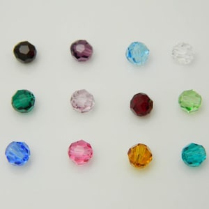 May include: Assortment of 12 faceted glass beads in various colors, including black, purple, light blue, clear, green, red, pink, orange, and teal.