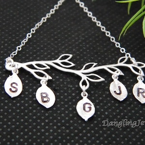 May include: Silver necklace with a branch design and five leaves with initials S, B, G, J, and R hanging from it.
