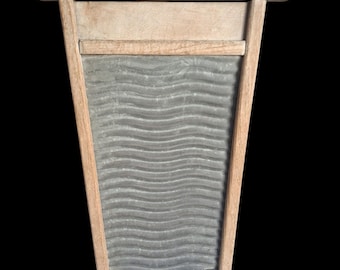 May include: A rectangular washboard featuring a light-coloured wooden frame and a central corrugated metal scrubbing surface with horizontal wavy ridges. A small metal eyelet hook is attached to the top centre of the wooden frame.