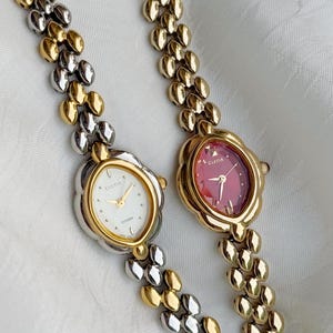 Puede incluir: Dos relojes Cletia Citizen vintage. Uno tiene esfera blanca y el otro roja. Ambos tienen correas doradas y plateadas. Las esferas son ovaladas con un diseño floral.