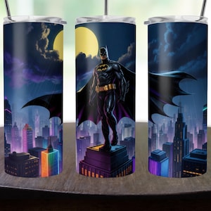 May include: A stainless steel tumbler featuring a Batman design. The artwork depicts Batman standing on a rooftop overlooking a cityscape at night. The background includes a full moon, rain, and colorful neon lights. The tumbler has a silver lid and a straw.