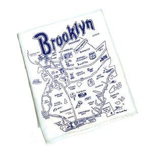 May include: A white tea towel with a blue and white illustration of a map of Brooklyn, New York. The map includes various landmarks and neighborhoods, such as Prospect Park, Coney Island, and Williamsburg.