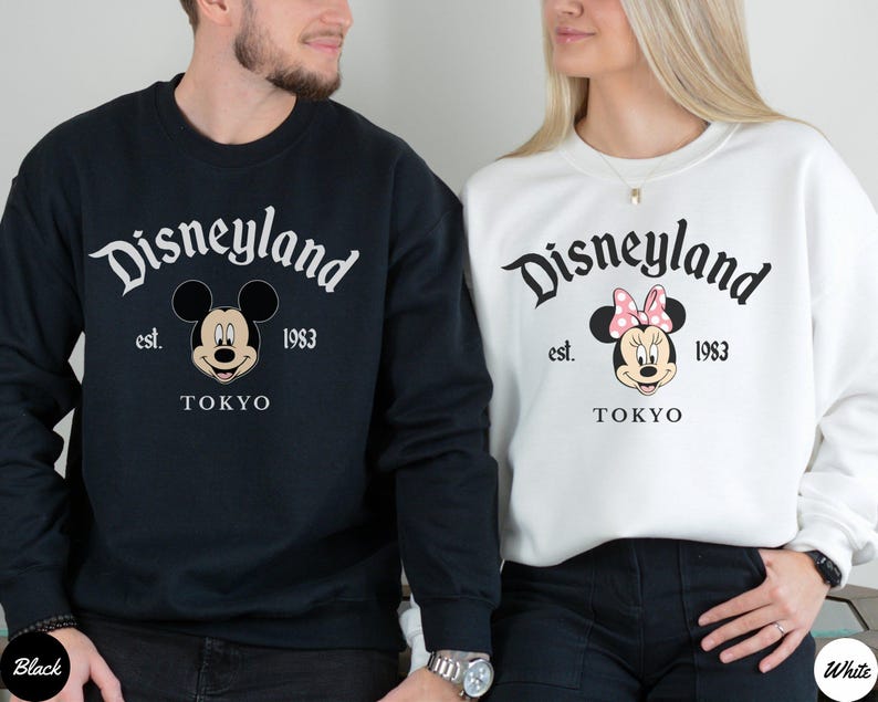 May include: Black and white sweatshirts featuring the Disneyland logo, Mickey Mouse and Minnie Mouse. The sweatshirts have the text "Disneyland est. 1983 TOKYO". The Mickey Mouse sweatshirt is black, and the Minnie Mouse sweatshirt is white.