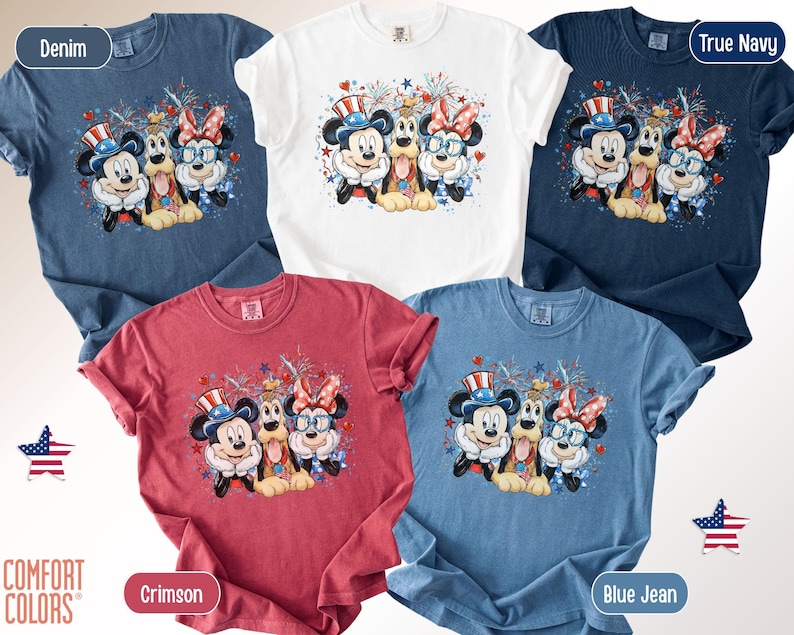 May include: Five Comfort Colors t-shirts in denim, white, true navy, crimson, and blue jean. Each shirt features a graphic of Mickey Mouse, Minnie Mouse, and Pluto in patriotic attire with fireworks.