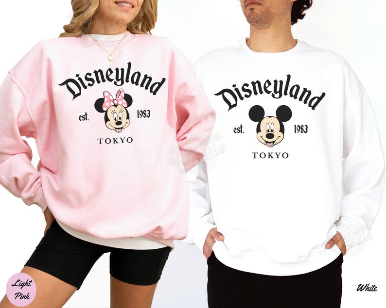 May include: Two sweatshirts, one light pink and one white, featuring the Disneyland logo with Mickey and Minnie Mouse. The text includes "est. 1983" and "TOKYO". The Minnie Mouse design has a pink bow.