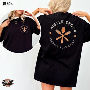 May include: Black t-shirt with the text "MISTER SPOON PREMIUM FOOD COURT" in a circular design on the back and a smaller version on the front. The design features a spoon and two crossed forks. The shirt is a comfortable, oversized fit.