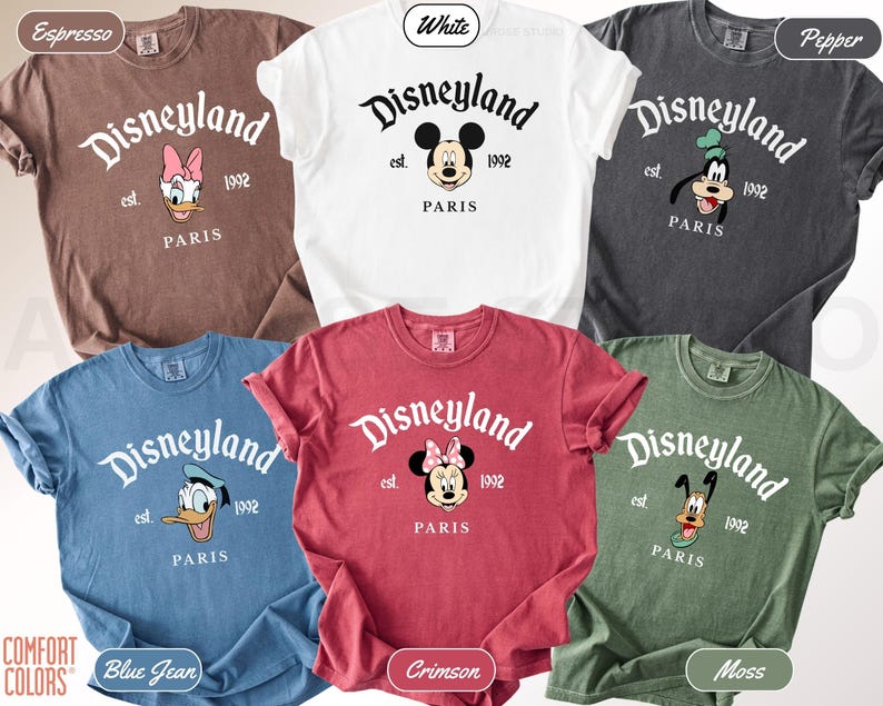 May include: A collection of six Comfort Colors t-shirts in various colors, including white, espresso, and blue jean. Each shirt features the Disneyland logo with a character graphic and the text "PARIS" and "1992".