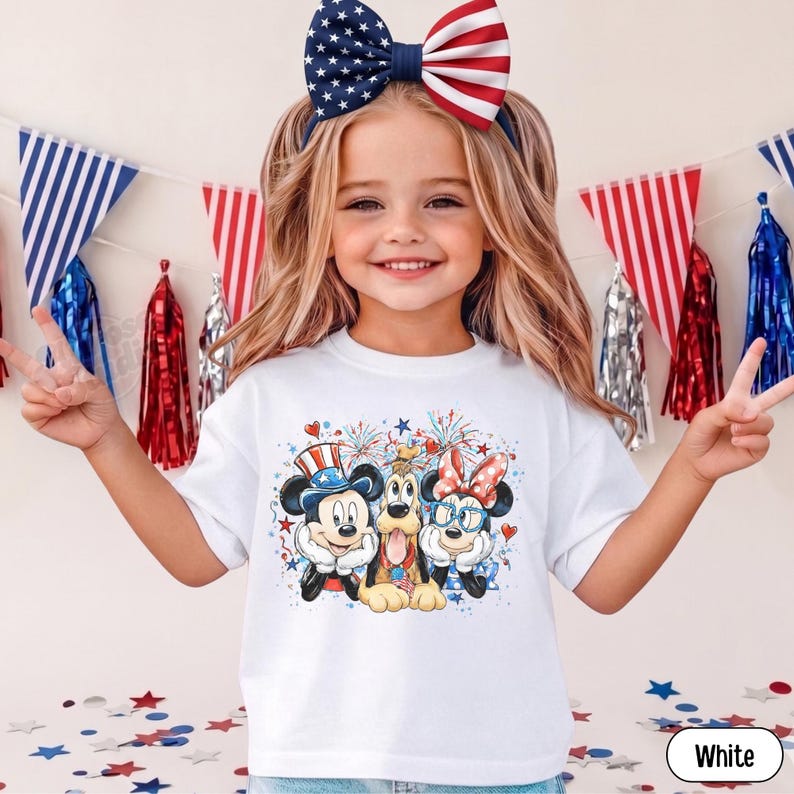 May include: A white t-shirt featuring Mickey Mouse, Pluto, and Minnie Mouse in patriotic attire. The design includes fireworks, hearts, and stars. The child is wearing a headband with a large red, white, and blue bow.