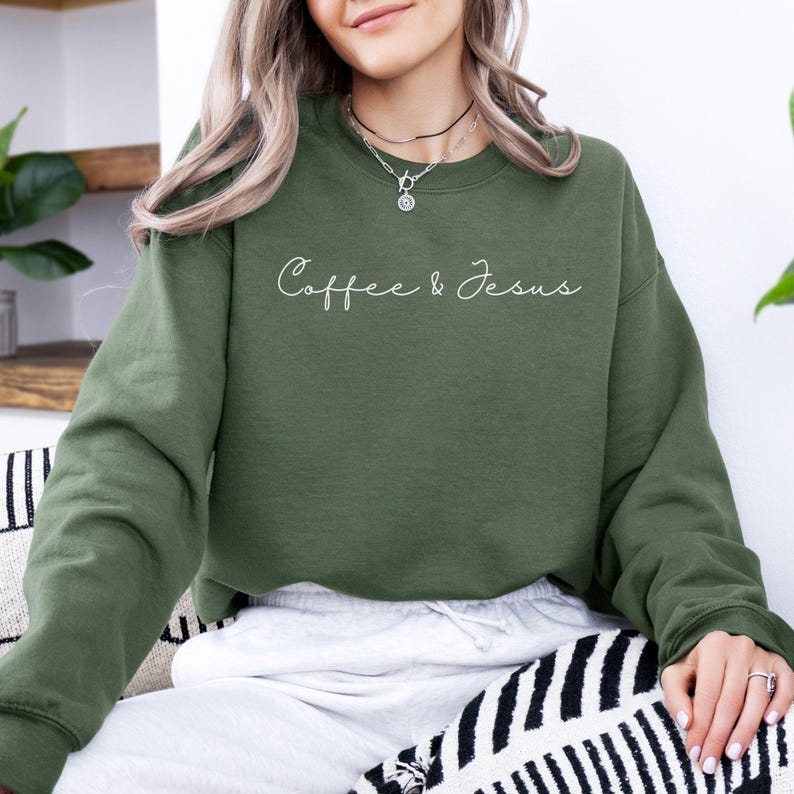 Puede incluir: Sudadera verde oliva con el texto "Coffee & Jesus" en cursiva. La parte superior de manga larga est&aacute; hecha de un material suave y es adecuada para ropa informal. La sudadera es de color liso.