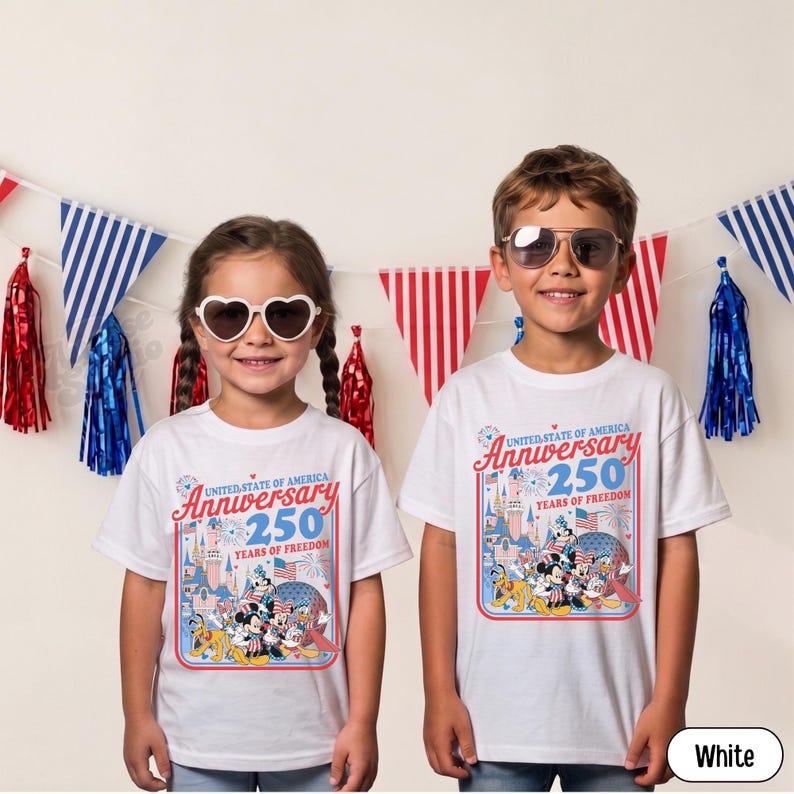 May include: Two children wearing white t-shirts with a colorful graphic celebrating the United States of America's 250th Anniversary. The design includes cartoon characters, fireworks, and the text "Anniversary 250 Years of Freedom."