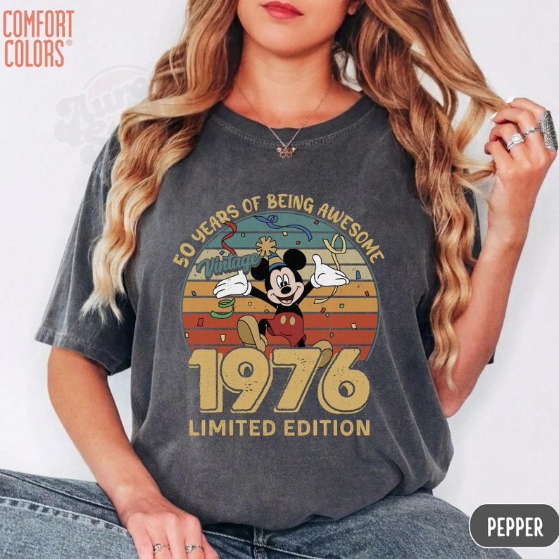 Puede incluir: Camiseta gris oscuro Comfort Colors con un dise&ntilde;o vintage de Mickey Mouse. El dise&ntilde;o incluye a Mickey Mouse, el a&ntilde;o 1976 y las palabras "50 Years of Being Awesome" y "Limited Edition."