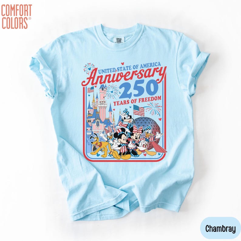May include: Light blue t-shirt with a graphic celebrating the United States of America's 250th Anniversary. The design features Disney characters, fireworks, and the text "United State of America Anniversary 250 Years of Freedom."