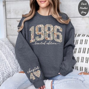 May include: Dark heather gray sweatshirt with the year "1986" in a floral design, the words "limited edition" below, and "chapter 40" on the sleeve. The sweatshirt is a crew neck style.