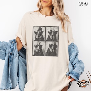 Op de afbeelding: Ivoor kleurig T-shirt met een vierpaneels afbeelding van een haan met zonnebril. Het shirt heeft een relaxte pasvorm en opgerolde mouwen. De tekst "Ivory" staat rechtsboven. Het Aurose Studio logo staat rechtsonder.