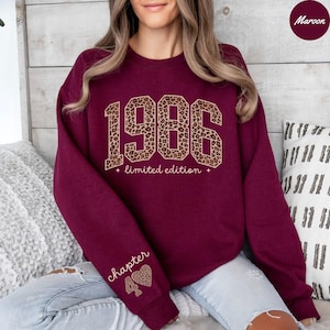 Op de afbeelding: Bordeaux sweatshirt met het jaar "1986" in luipaardprint, de woorden "limited edition" eronder en "chapter 40" op de mouw. De sweatshirt heeft een ronde hals.