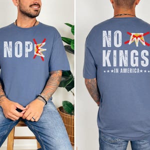 May include: Indigo blue t-shirt with the text "NOPE" and "NO KINGS IN AMERICA" in white. The word "NOPE" has a red "X" through the word and a crown. The back of the shirt has the same design.