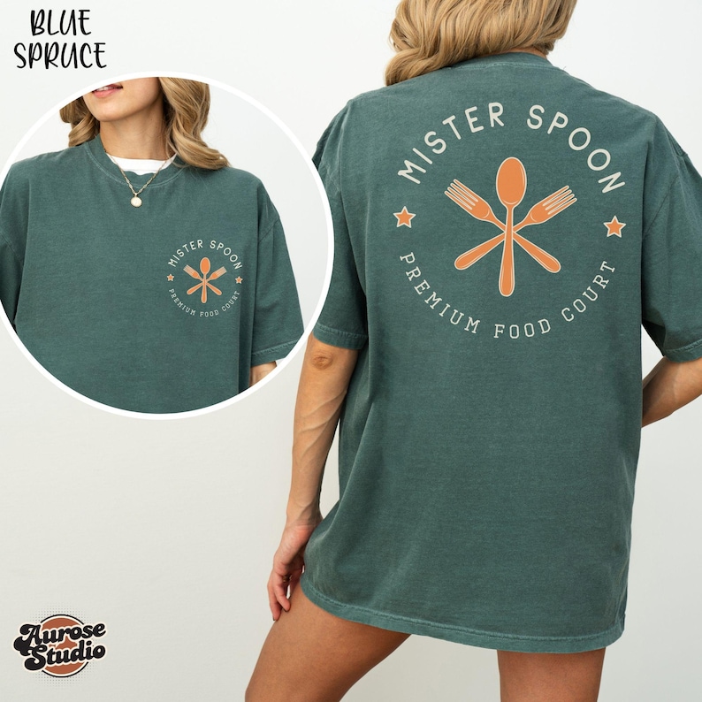 May include: A teal-colored t-shirt with the text "MISTER SPOON PREMIUM FOOD COURT" in a circular design on the back. The design includes a crossed spoon and forks in orange. The front of the shirt has a smaller version of the logo.