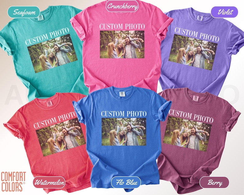 K&ouml;nnte beinhalten: Eine Auswahl an Comfort Colors T-Shirts in verschiedenen Farben, darunter Seegr&uuml;n, Pink, Lila, Rot, Blau und Beere. Jedes Shirt zeigt einen individuellen Fotodruck mit dem wei&szlig;en Text "CUSTOM PHOTO".