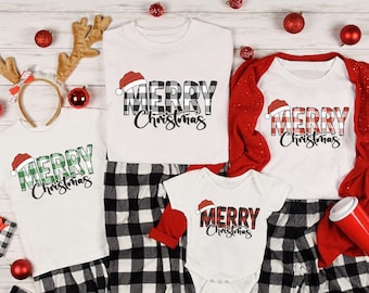 May include: White Christmas-themed shirts and pajamas with the text "MERRY Christmas" in a plaid design. The shirts have a Santa hat graphic. The pajamas are black and white checkered. Red Christmas ornaments and reindeer antlers are also visible.