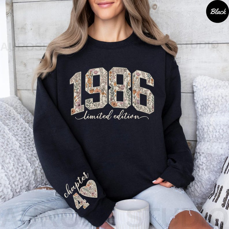 May include: Black sweatshirt with the year "1986" in a floral design. The words "limited edition" are below the year. The left sleeve has the words "chapter 4" and a floral heart design. The sweatshirt is a limited edition.