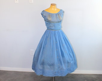 May include: A light blue vintage dress with a fitted bodice and a full skirt. The dress has a scoop neckline and cap sleeves. The bodice is decorated with a gold embroidered design.