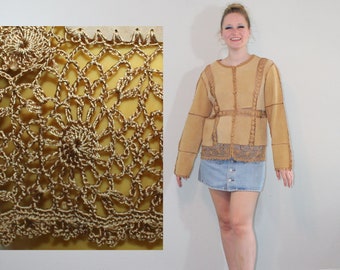 May include: A woman wearing a brown suede jacket with a lace trim and a denim skirt. She is standing on a wooden floor in front of a wall with a crocheted wall hanging.