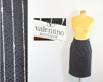 May include: Black and white striped skirt with a Valentino Boutique label. The skirt is on a mannequin and the fabric has a textured pattern.