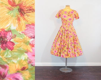May include: A vintage floral dress with a yellow, pink, and green floral print. The dress has a fitted bodice and a full skirt. It is displayed on a mannequin.