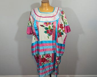 May include: A white, short-sleeved dress with floral embroidery and colorful ribbon accents. The dress features pink, blue, and white ribbons, with a square neckline and a knee-length hemline. The dress is displayed on a mannequin.