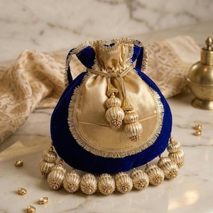 Peut inclure: Une pochette en velours bleu avec un panneau avant en satin doré et une bordure dorée. La fermeture à cordon est dorée, avec des glands dorés. Une rangée d'ornements perlés dorés est au bas de la pochette. Décoratif, élégant et orné.