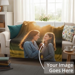 Op de afbeelding: Een gepersonaliseerde deken met een afgedrukte afbeelding van een moeder en dochter, gedrapeerd over een witte bank. De deken heeft een warme, goudkleurige achtergrond. De tekst "Your Image Goes Here" staat onderaan.