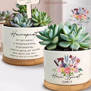 May include: Two white ceramic pots with succulents, each on a wooden base. One pot has the word "Hairapist" and a definition. The other pot says "Hair Stylist" with a name. Both pots have a wooden or clear sign that says "Hair Stylist" and a name.