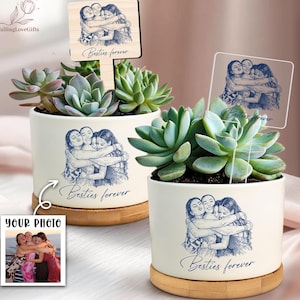 May include: Two white ceramic planters with succulents, each featuring a blue sketch of three people hugging and the text "Besties forever." One planter has a wooden sign with the same image. The other has a clear acrylic sign.