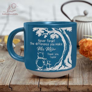 May include: A teal ceramic mug with a white tree and bear illustration. The mug has the text "Never forget the difference you make. Mrs. Miller. Thank you, Taylor." The mug has a beige base and a teal handle.