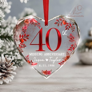May include: A heart-shaped clear acrylic ornament hanging from a red ribbon. It features the red text 40th, the words WEDDING ANNIVERSARY, the names Jason and Taylor with a heart symbol, and the date 6.11.1986, surrounded by red floral graphics.