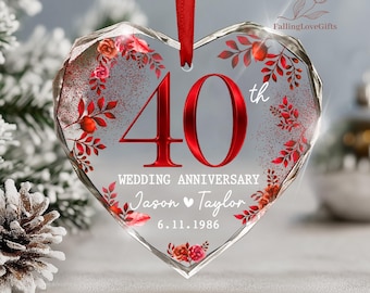 May include: A heart-shaped clear acrylic ornament hanging from a red ribbon. It features the red text 40th, the words WEDDING ANNIVERSARY, the names Jason and Taylor with a heart symbol, and the date 6.11.1986, surrounded by red floral graphics.