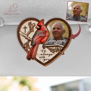 May include: A heart-shaped wooden memorial ornament featuring a red cardinal perched on a branch, a photo of a person, and the text "I'm always with you." Includes a cross and the name "Agatha Anderson 1953-2026".