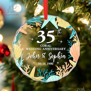 May include: A clear, round ornament with a red ribbon, featuring a coral reef design. The ornament commemorates a 35th wedding anniversary, with the names "John & Sophia" and the date "09.18.1990" displayed in elegant script.