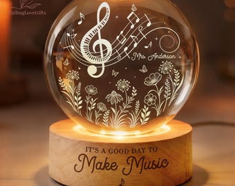 Può includere: Una sfera di vetro illuminata con note musicali, una chiave di violino e motivi floreali, posta su una base di legno. La base recita "IT'S A GOOD DAY TO Make Music". La sfera è illuminata dall'interno.