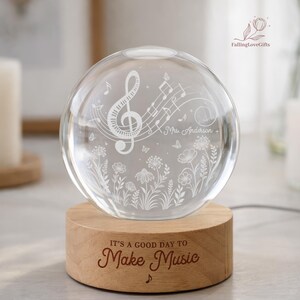 Pu&ograve; includere: Una sfera di vetro trasparente con note musicali e motivi floreali, appoggiata su una base di legno. La base &egrave; incisa con la frase "IT'S A GOOD DAY TO Make Music". La sfera presenta una chiave di violino e il nome "Mrs. Anderson".