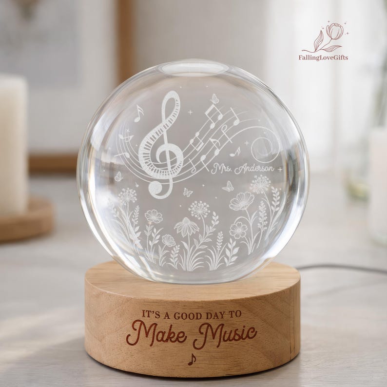 Pu&ograve; includere: Una sfera di vetro trasparente con note musicali e motivi floreali, appoggiata su una base di legno. La base &egrave; incisa con la frase "IT'S A GOOD DAY TO Make Music". La sfera presenta una chiave di violino e il nome "Mrs. Anderson".