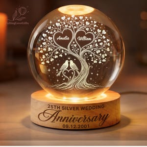 May include: A clear glass sphere lamp featuring an internal laser-etched tree with heart-shaped leaves, two birds, and the names Amelia and William. The wooden base is engraved with 25TH SILVER WEDDING Anniversary and the date 09.12.2001.