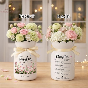 May include: A white ceramic vase with a floral arrangement of pink and white flowers. The front of the vase has the name "Taylor" and a floral design. The back of the vase says "Chapter Sixty" and has a birthday message.