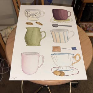 May include: Watercolor illustration of various teacups, a pitcher, and cookies. The teacups are in different colors and styles, including floral patterns and striped designs. A spoon and a tea bag are also included in the image.