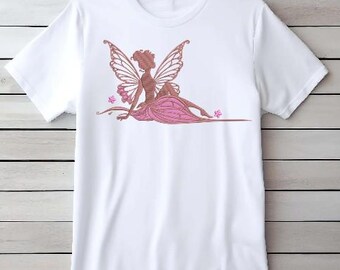 May include: White t-shirt featuring an embroidered fairy design. The fairy has detailed wings and is wearing a pink dress. The design includes pink flowers. This tee is perfect for those who love fantasy and fairy-themed apparel.