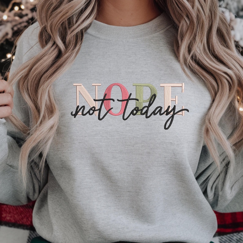 May include: A light gray sweatshirt with the embroidered text "NOPE not today". The word "NOPE" is in a pastel color scheme, with the letters in pink, green, and beige. The phrase "not today" is in a black script font.