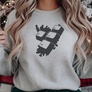 Peut inclure: Un sweat-shirt gris clair avec un motif graphique gris fonc&eacute; de touches de clavier d'ordinateur : A, S, D et W. Les touches sont dispos&eacute;es en grappe avec un motif &eacute;clabouss&eacute;. C'est un v&ecirc;tement d&eacute;contract&eacute; et confortable.