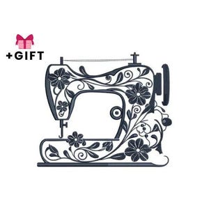 以下が含まれることがあります： 花柄の装飾が施された濃い灰色のミシンデザイン。ミシンは花とつるの装飾的なパターンが特徴です。画像には「+ギフト」という文字とピンクのギフトボックスのアイコンが含まれています。